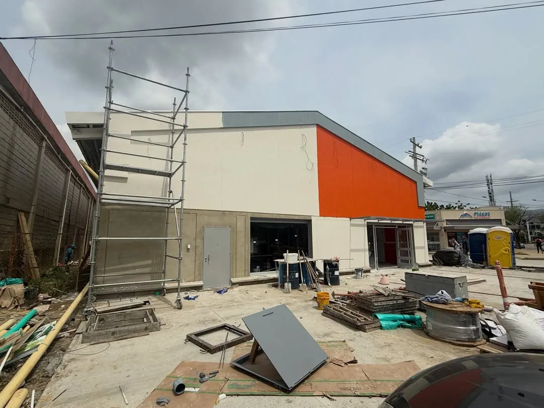 Fachada de la tienda ARA Curinca durante la ejecución de obra, con andamios y materiales.